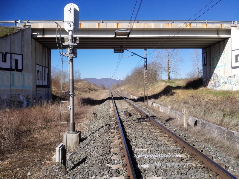 Imagen del tren actual a su paso por Sakana, se puede apreciar el espacio dejado para instalar otra vía, a la izquierda de la imagen, tanto en el puente como en la trinchera...
